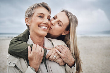 Kiss, mother and daughter at beach smile, hug and kiss with smile together in Australia. Happy face of young woman with a senior mom in the sea or ocean together with love and to relax in happiness - obrazy, fototapety, plakaty