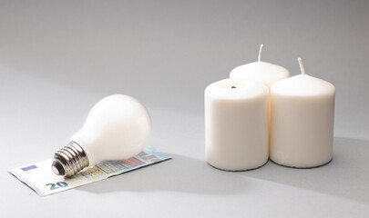 white candle and light bulb on top of 20 euro banknotes, gray background