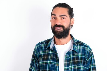 young bearded hispanic man wearing plaid shirt over white background being nervous and scared...
