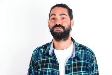 young bearded hispanic man wearing plaid shirt over white background puffing cheeks with funny face. Mouth inflated with air, crazy expression. - obrazy, fototapety, plakaty