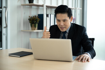 Fototapeta premium Online learning, Meeting, working and E learning concept. Casual Asian business man studying online course, meeting via laptop computer in the office.