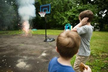 Brothers looking at fireworks while standing in backyard