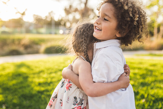 Side View Of Happy Siblings Embracing At Park