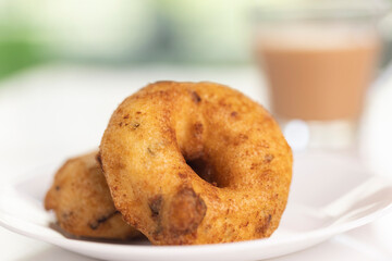 plate of methu vadai with cup of tea on table.