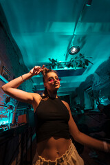 Beautiful female DJ dancing to techno in a small club - obrazy, fototapety, plakaty