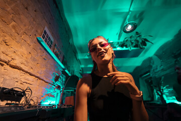 Beautiful female DJ dancing to techno in a small club - 541000205