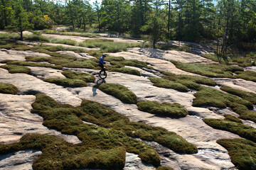 A man rides his mountain unicycle on exposed granite of the Cedar Rock Trail in the Dupont State Forest near Brevard, NC.