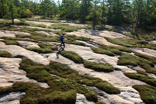 A Man Rides His Mountain Unicycle On Exposed Granite Of The Cedar Rock Trail In The Dupont State Forest Near Brevard, NC.