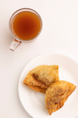 Plate of hot Samosas and cup of tea on table 