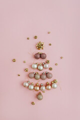 Creative Christmas fir tree made of holiday decorations on pink background. New Year greeting card. Flat lay, top view