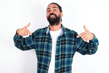 Fototapeta premium Pick me! Confident, self-assured and charismatic young bearded hispanic man wearing plaid shirt over white background promoting oneself as wanting role smiling broadly and pointing at body.