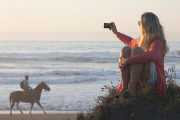 Mature woman takes photo of chilean cowboy on shoreline