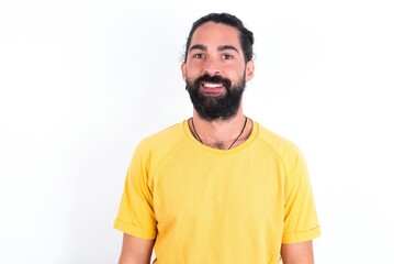 Fototapeta premium young bearded hispanic man wearing yellow T-shirt over white background with nice beaming smile pleased expression. Positive emotions concept