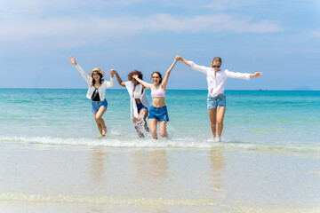 Photo of a group of girls of different ethnicities running and having fun together at the beach. on a fresh day