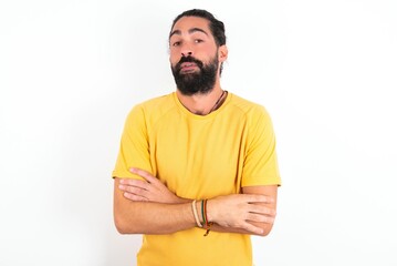 Fototapeta premium young bearded hispanic man wearing yellow T-shirt over white background shaking and freezing for winter cold with sad and shock expression on face.