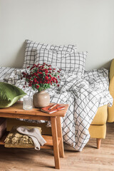 Morning in the bedroom - a cozy bed with linen sheets in a cage, a wooden bench with flowers, blankets and decor