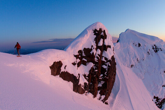 Skier hiking on high alpine ridge at sunet.