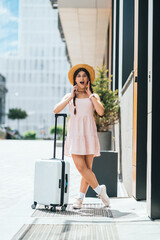 Portrait of young woman with suitcase and looking at camera - 541004627