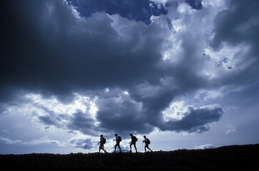 Four adults hike along a mountain ridge while participating in an adventure race. Telluride,  Colorado
