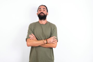 Serious pensive young bearded hispanic man wearing green T-shirt over white background feel like cool confident entrepreneur cross hands.