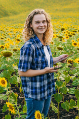 Farmer woman examining the field of sunflowers and sends data to the cloud from the digital tablet. Smart farming and digital agriculture. Agricultural worker
