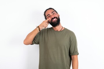 young bearded hispanic man wearing green T-shirt over white background pointing unhappy to pimple...