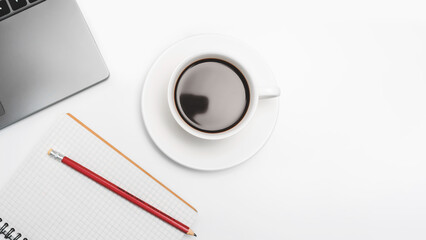 Coffee cup on white desk with laptop and notepad, top view