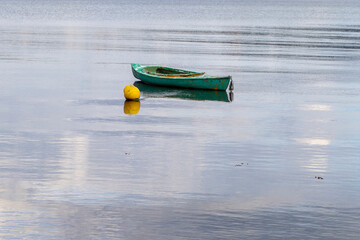Green little boat on the sea and a yellow buoy