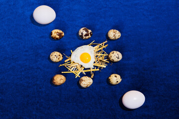 Food pop art photography. Composition with quail and chicken eggs on bright blue tablecloth. Retro style, colorful minimalism, art, creativity