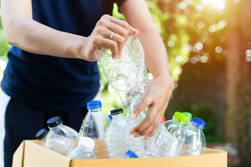 Hand hold and crushing plastic bottle for recycle.In garden background.