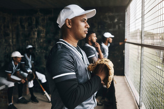 Baseball, training and coach in dugout, thinking and serious ,planning and sports strategy. Sport, stadium and goal vision by team trainer watching game with baseball player group in background