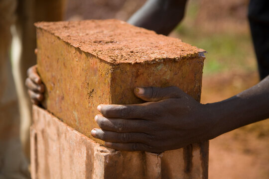 Hands lifting a homemade mud brick