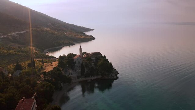 The aerial drone footage over the church in Brac Island at sunrise is simply stunning. The church is set against the backdrop of the calm sea and the sky is ablaze with the colors of the rising sun. 