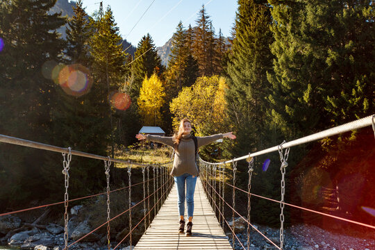 Girl traveler on suspension bridge in the background of the forest
