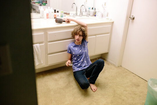 Teen Girl Holds Toothbrush And Reaches For A Hairbrush While Seated