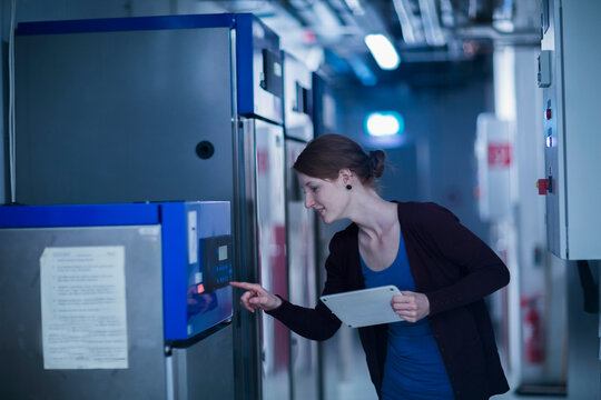 Young female engineer using a digital tablet and controlling a switchgear in control room, Freiburg im Breisgau, Baden-W&uuml;rttemberg, Germany