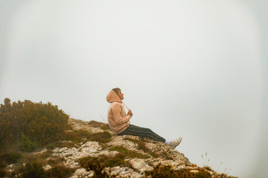 Young boy sitting on a rock looking towards the horizon