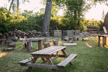 Backyard stuff. Picnic zone. Rural gardening. Sunshine yard with wooden table and bulk logs keeping...