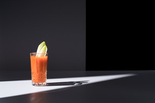 Vaso de jugo de zanahoria con hojas de endibia sobre fondo oscuro	