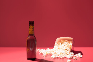 Una caja de palomitas de maíz con una botella de cerveza sobre un fondo rojo