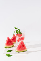 Vaso de zumo de sandía con trozos de sandia y hielo sobre fondo claro	