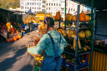 Obraz na płótnie Canvas Female farmer carries a wooden box for small pumpkins