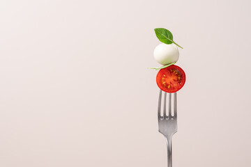 Fork with tomato, mozzarella cheese and basil. Caprese salad on fork close up view. Italian food...