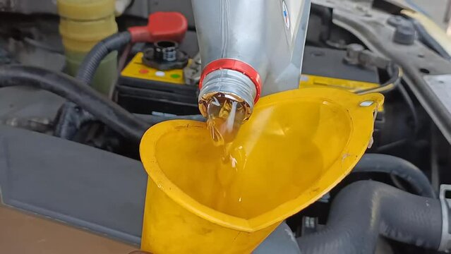 An engine mechanic fills the engine with lubricant.
