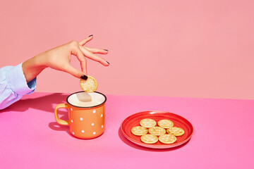 Goodies. Food pop art photography. Young girl tasting milk with crackers isolated over pink background. Concept of food, creativity.
