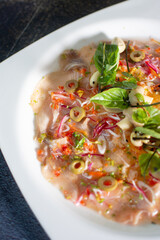 Fish carpaccio. Finely sliced ​​fish. Tuna and needle fish. Garnished with Olive Oil and Capers