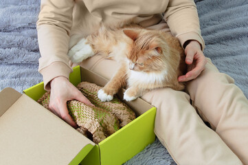 Unpacking the parcel. Caucasian woman sitting on  bed with a cat.