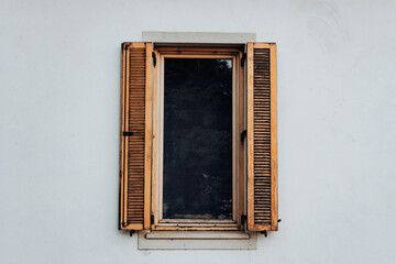 Vintage open window wood shutter on a white wall of a rustic home