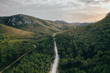 Fototapeta premium Drone view of savage road in the middle of the green forest and mountains