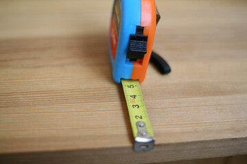 Carpenter's tape measure on a wooden board close-up. Distance meter in centimeters. Homework woodwork and repair